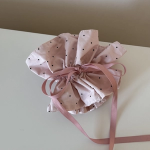 Close-up of pink polka dot fabric drawstring pouch with a satin ribbon bow detail