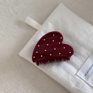 Macro shot of a dark burgundy heart-shaped hair claw clip with white polka dots pattern
