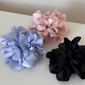 Detailed view of satin hydrangea floral scrunchies in blue, pink, and black colors
