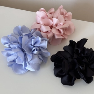 Detailed view of three layered satin floral hair ties in blue, pink, and black