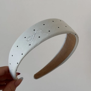Detail of white satin headband with black polka dots and silver bow embroidery