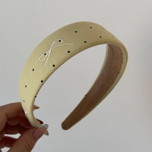 Detail of beige polka dot headband with delicate white bow embroidery and velvet lining