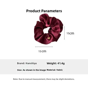 Detail of dark red silk scrunchie with a gold oval metal tag and 15cm diameter size info