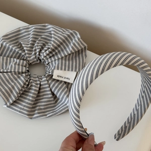 Close-up of hair accessory set with grey striped scrunchie and headband on white background