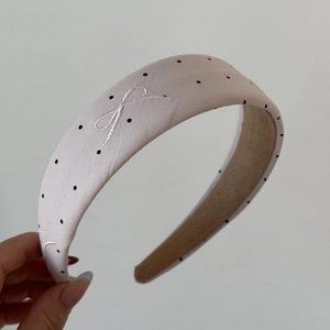 Close-up of beige polka dot hairband featuring exquisite white bow embroidery details