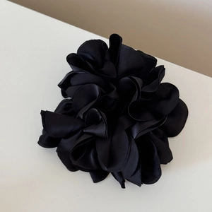 Macro view showing the glossy black satin fabric and petal layers of the flower hair tie