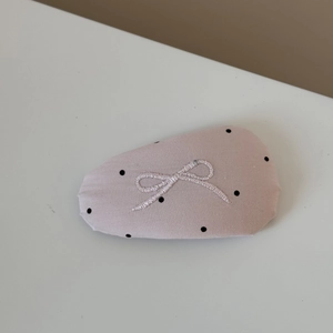 Detail of pink fabric hair clip with black polka dots and white bow embroidery
