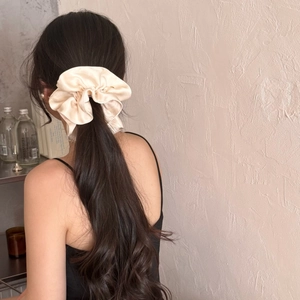 Elegant oversized cream silk scrunchie shown in a low ponytail with glossy satin texture