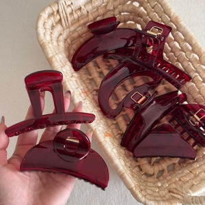Detail of dark red translucent hair claw clips set in a woven basket display