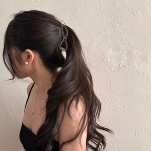 Elegant French hollow bow banana clip in amber texture worn on a brunette ponytail