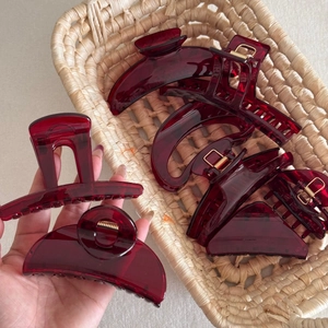 Detail view of various translucent red resin hair claws with golden metal springs