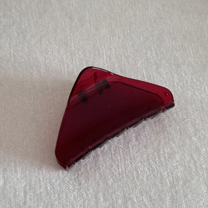 Detail view of triangular translucent burgundy hair claw clip with metallic spring