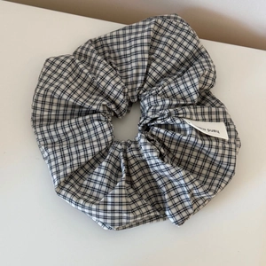Detailed shot of black and white plaid oversized scrunchie with a handmade woven label