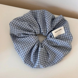 Detail of blue and white checkered scrunchie with a hand made woven label on the fabric