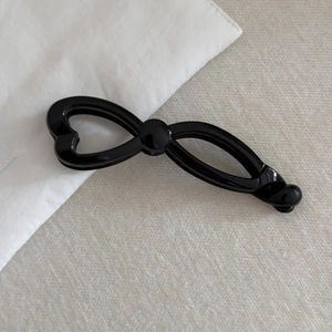 Detail view of large black French bow banana hair clip on light textured fabric background