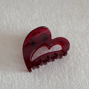 Detailed view of a transparent red heart-shaped hair claw clip on white fabric