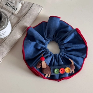 Détail d'un chouchou en jean bleu avec poupée teckel mignonne et boutons colorés