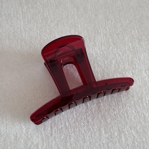 Close-up of translucent deep red resin hair claw clip with glossy finish and spring detail