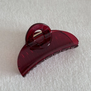 Detailed view of the dark red translucent resin hair claw with sturdy metal spring mechanism