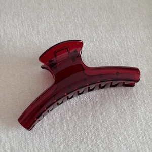 Close-up of a translucent dark red hair claw clip with a glossy finish and metal spring