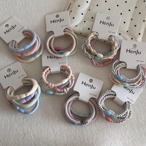 Detail of multi-strand braided hair ties in Morandi colors with candy-shaped buckles