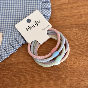 Close-up of 5-piece macaron colored elastic hair bands with frosted beads on a wood desk