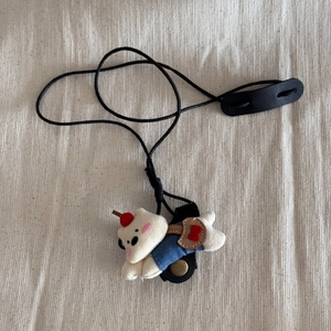 Detail of cute plush dog glasses holder necklace with blue denim outfit and black lanyard