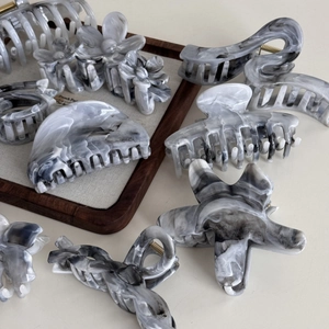 Detail view of acetate hair claws in marble gray ink pattern with diverse geometric shapes