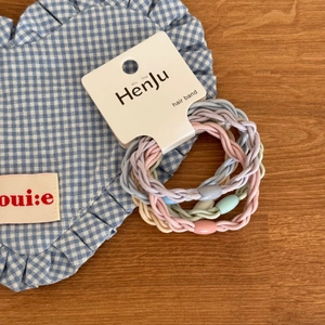 Close-up of colorful woven macaron hair ties with translucent beads on a card