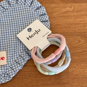 Close-up of macaron-colored elastic hair bands with smooth beads on a display card