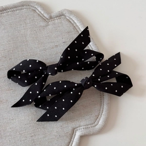 Coppia di eleganti fermagli per capelli a fiocco neri con pois su sfondo neutro