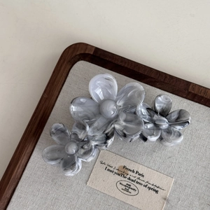 Detail view of large marble texture acetate hair claw clip with triple 3D flower design
