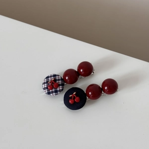 Detailed close-up of cherry theme hair clips with navy plaid and glossy red beads