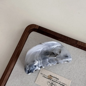 Detail of grey and white marble pattern hair claw clip on a minimal wooden linen tray