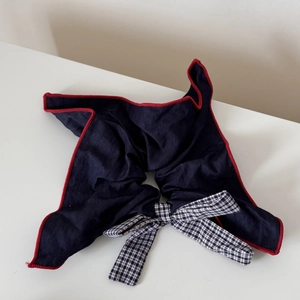 Detailed close-up of navy blue fabric hair clip featuring a plaid bow and red stitching