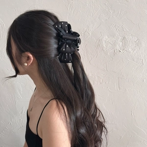 Pince à cheveux élégante en satin noir à pois blancs portée sur de longs cheveux