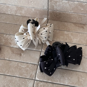 Détail de grandes pinces à cheveux à nœuds multicouches avec motif à pois noir et blanc