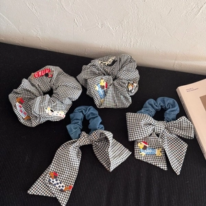 Détails de chouchous à carreaux avec broderie de chien et grand nœud décoratif