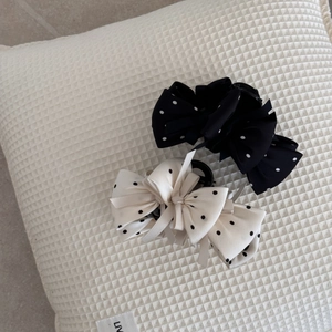 Gros plan de pinces à cheveux à nœuds à pois noirs et blancs sur un tissu texturé
