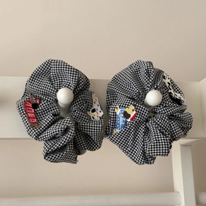 Détail de chouchous à carreaux noirs et blancs avec écussons chien sur un crochet