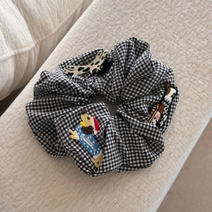 Détail du chouchou vichy avec broderies de chiens et patch festif de chapeau de Noël