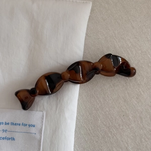 Détail d'une pince à cheveux banane écaillée en résine brillante sur tissu doux