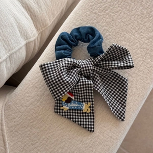 Gros plan sur chouchou bleu denim avec nœud vichy et broderie de chiot mignon