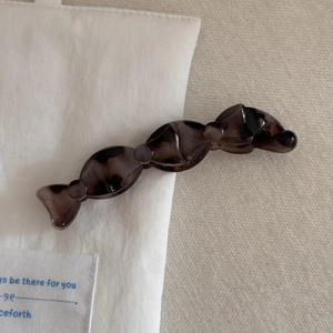 Vue détaillée d'une pince à cheveux ondulée en résine écaille sur tissu crème