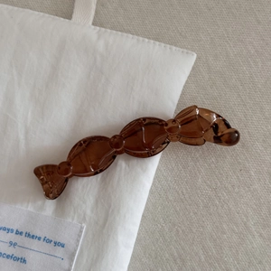 Vue détaillée de la pince à cheveux marron en forme de bonbon sur toile blanche