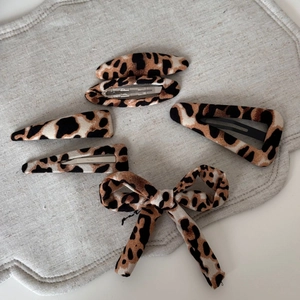Detail of five-piece set featuring leopard print hair clips and a matching bow hair tie