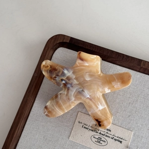 Vue détaillée de la pince à cheveux étoile de mer au motif marbré ambré