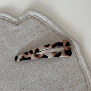 Macro detail of leopard print fabric hair clip on a heart-shaped textured base