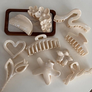 Detailed macro view of cream-white acetate hair claws in flower and starfish shapes