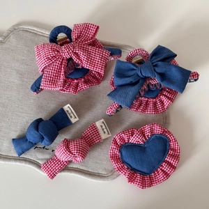 Detailed view of handmade denim and red plaid hair clips with heart and bow patterns